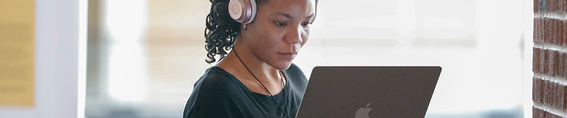 person wearing headphones working on a laptop computer
