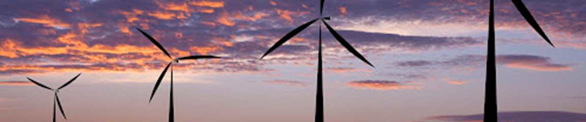 four windmills silhouetted against a sunset