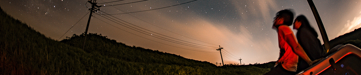two people stargazing from the roof of a car with powerlines in the background